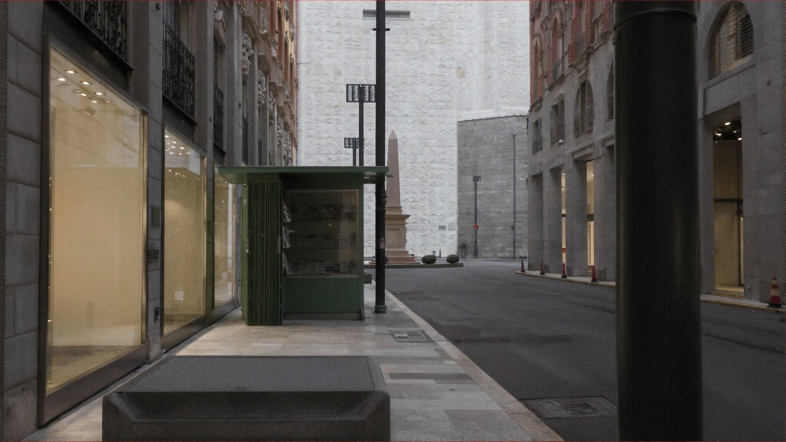 The same street from the same camera, now with newspapers visible inside the kiosk, carved stone window surrounds, wrought-iron balcony grilles, paving joints and drain covers