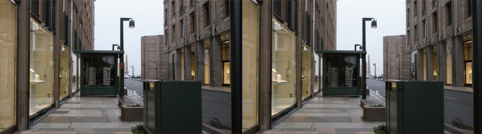 Two nearly identical photographs of an empty pavement beside a green newspaper kiosk. Both show the same dark, ambiguous shape inside the kiosk's window that could be a person, and no pedestrian anywhere else in either frame.