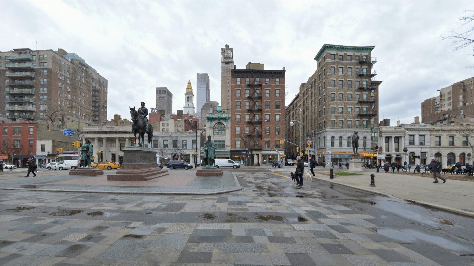 The same viewpoint after the fix: a very large open square of wet grey granite flags in bands and setts, the equestrian bronze and two standing bronzes on the left, benches and railings on the right, brick and terracotta blocks all round, a gold-capped bell tower at the far end